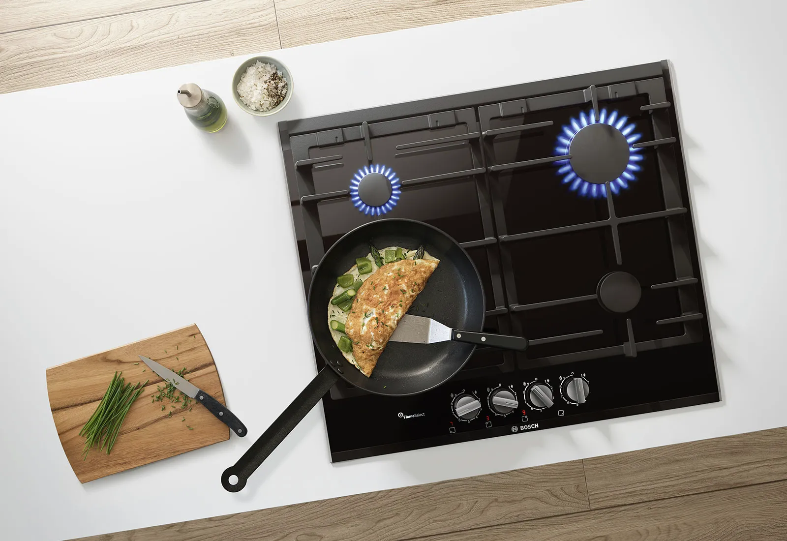 12511604A gas stove with blue flames and frying pan containing an omelet and vegetables, alongside cutting board with chopped herbs.