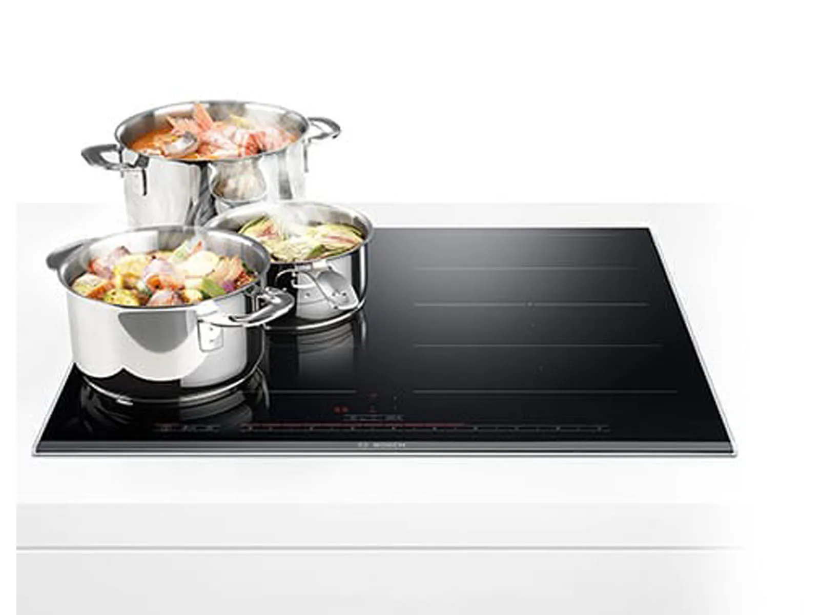 Black Bosch induction cooktop with three pots of food cooking.