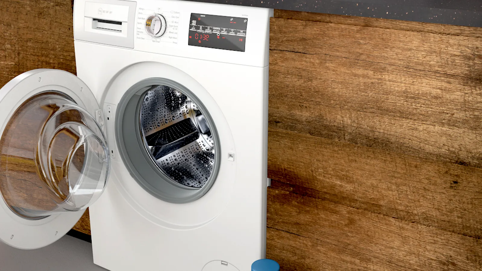 Washing machine with open door on wooden surface, showing interior drum.