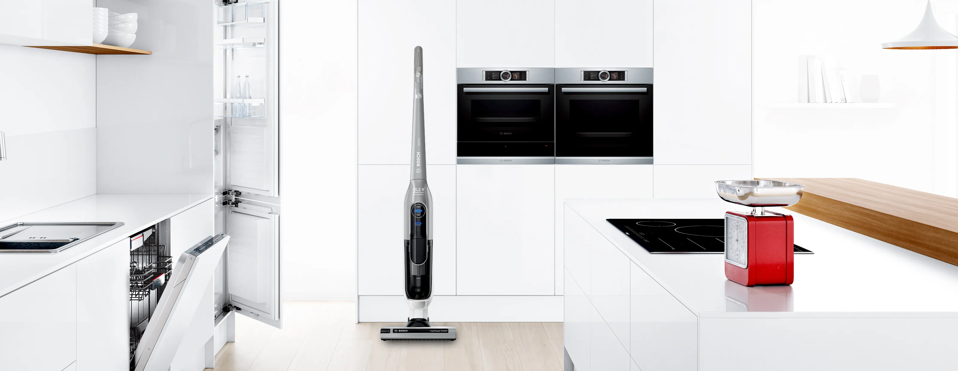 A Bosch cordless stick vacuum cleaner standing upright in a modern, bright white kitchen.