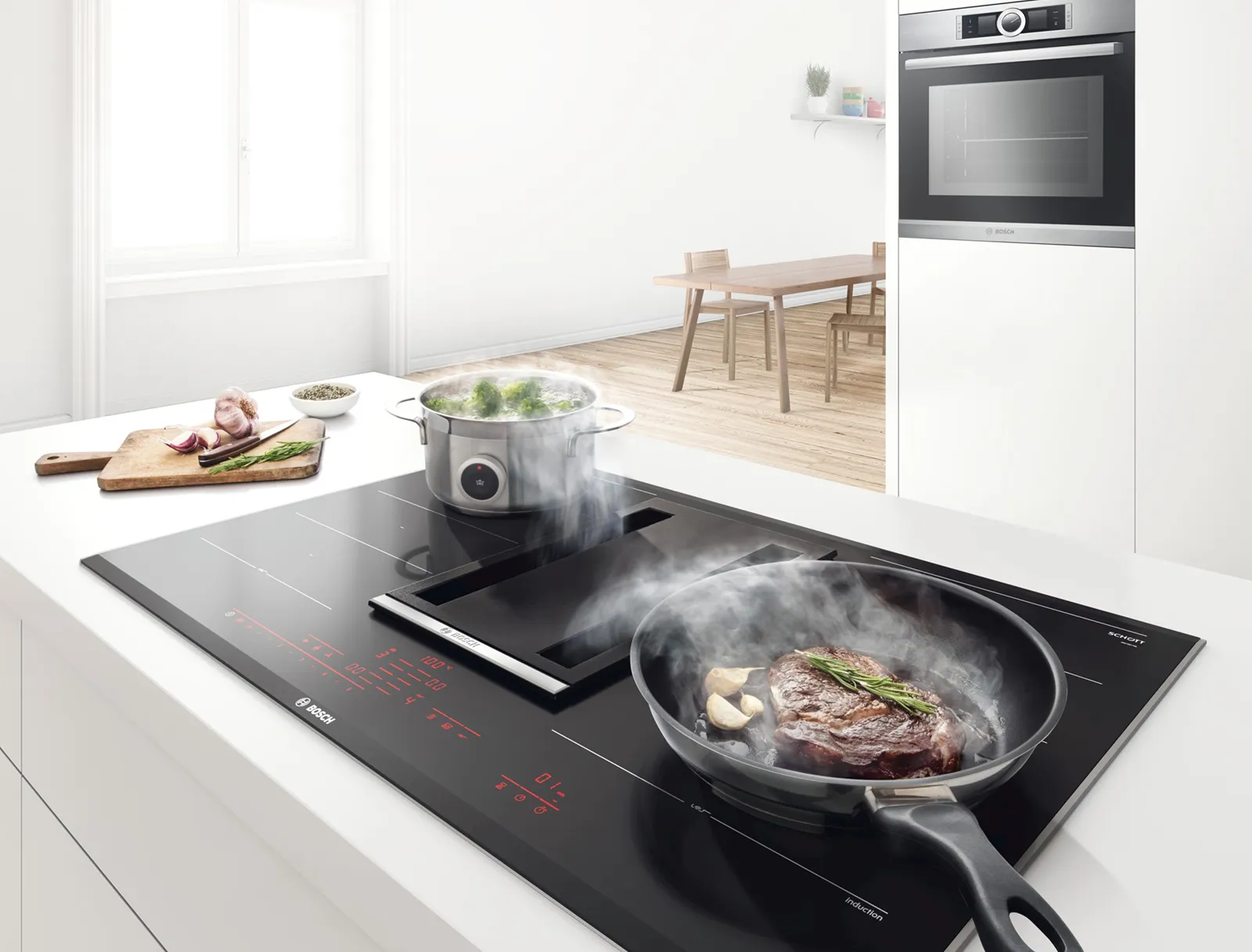 Bosch Induktionskochfeld mit integriertem Dunstabzug, auf dem Fleisch in einer Pfanne brät und Gemüse im Topf kocht.