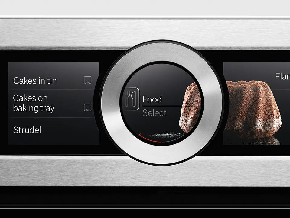 Close-up of a sleek oven control panel displaying food options like cakes and strudel, featuring a circular selection dial.