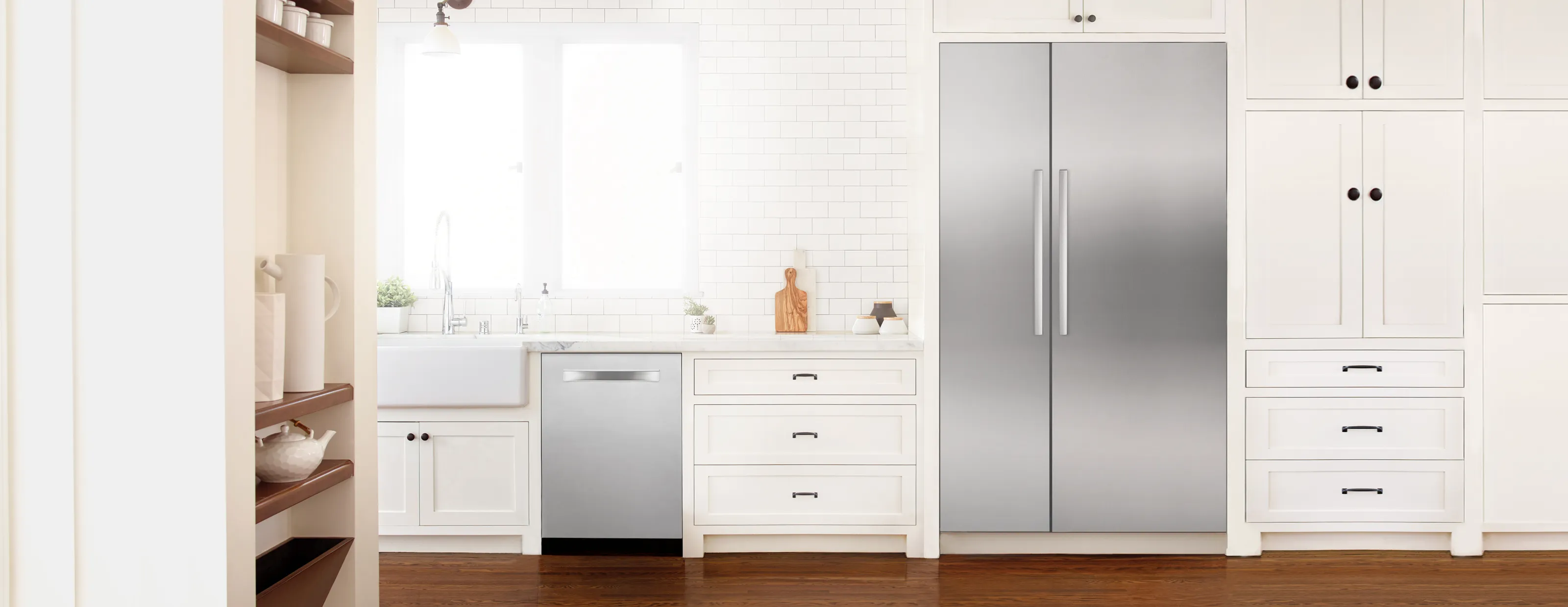 Modern kitchen with Bosch stainless steel appliances, white cabinets, and wooden flooring.