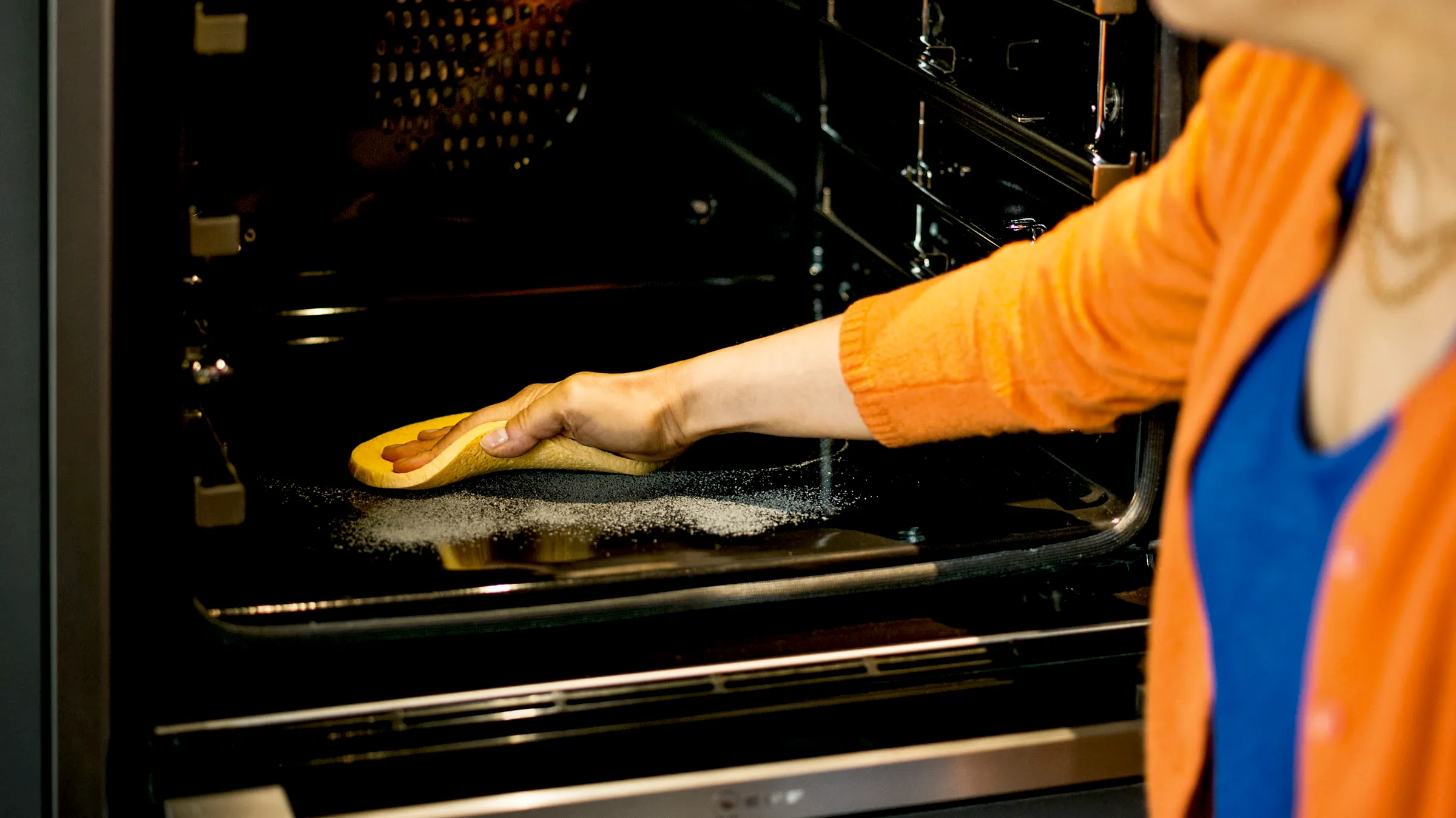 Frau wischt Pyrolyse Rückstände aus einem NEFF Backofen