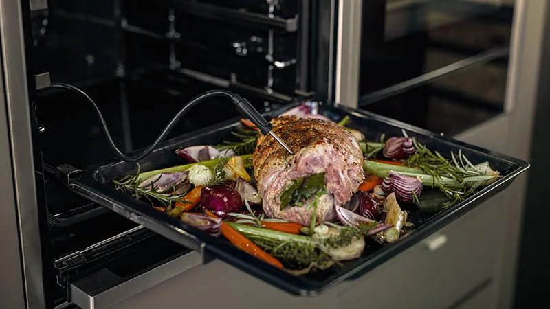 Roasted meat dish with vegetables in oven tray.