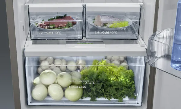 Interior de frigorífico Bosch com gaveta ExtraFresh cheia de vegetais e frutas frescas, como alface, cenouras e uvas, destacando a conservação.