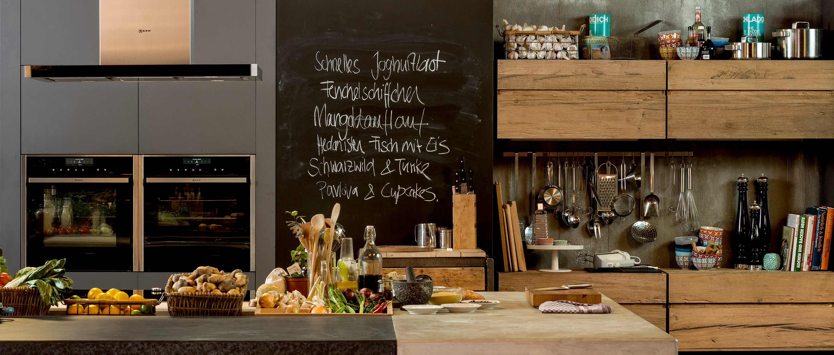 Ruime keuken met moderne apparatuur, houten planken, krijtbordmenu, en diverse kookgerei en ingrediënten.