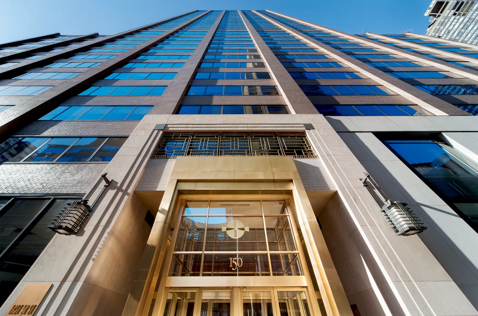 Tall glass and stone building with golden entrance and street number 150 visible.
