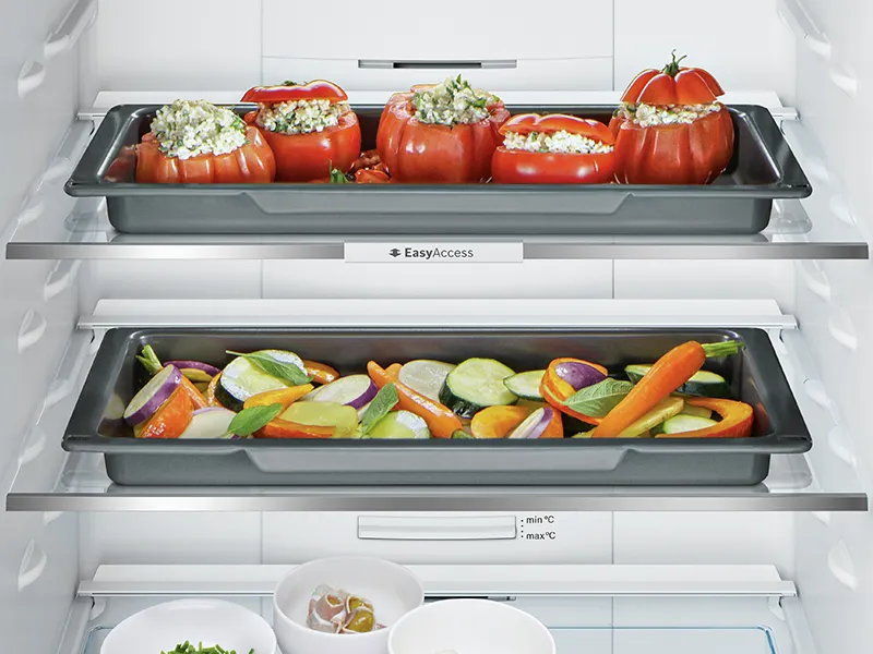 Frigorifero interno con peperoni ripieni e verdure assortite su ripiani.