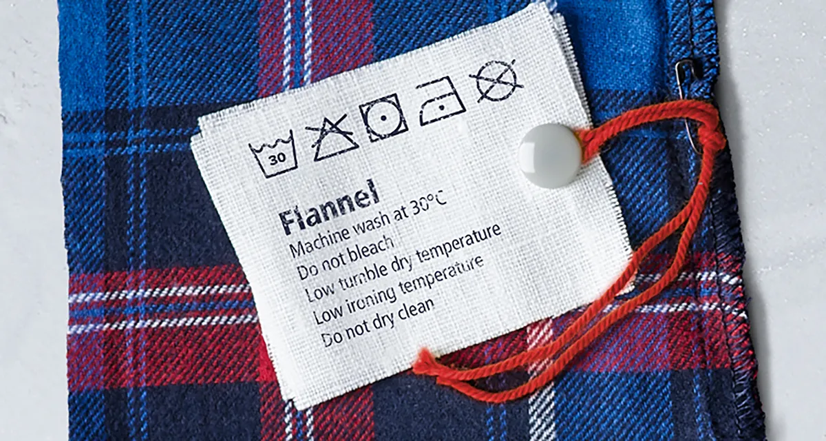 Flannel clothing label with washing instructions on a plaid fabric background.