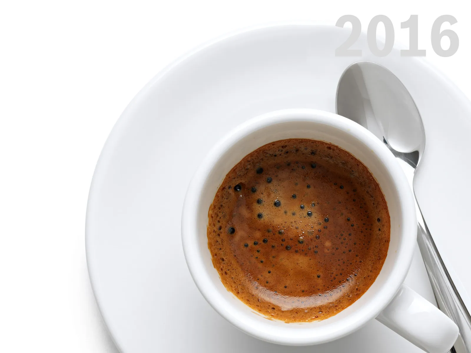 White cup of espresso with crema, on a saucer with a spoon. Year 2016 in corner.