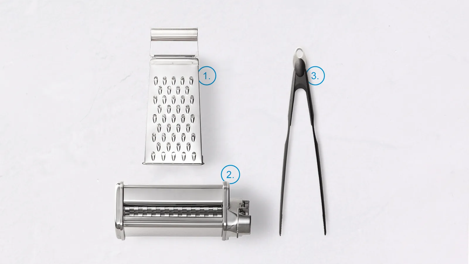 Kitchen tools: grater, tongs, and pasta maker on white background.
