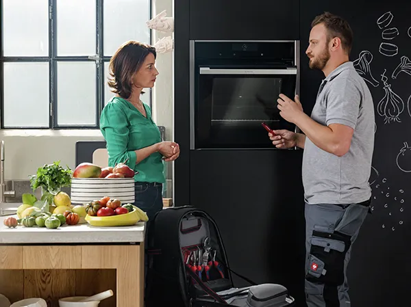Hombre técnico ayudando a una mujer en la cocina