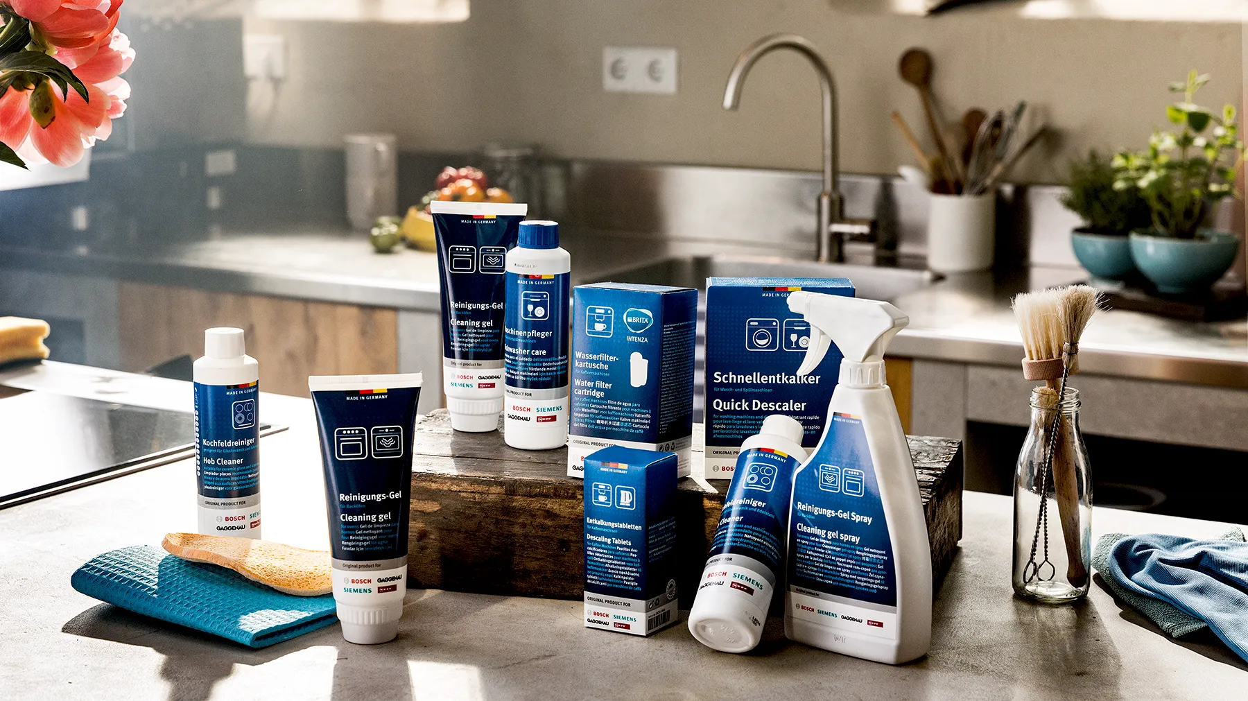 Küchentisch mit verschiedenen Reinigungs- und Hygieneprodukten, einschließlich Sprays, Flaschen und Bürsten.