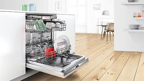 Integrated Bosch dishwasher built into a white kitchen island, open and filled with dishes.