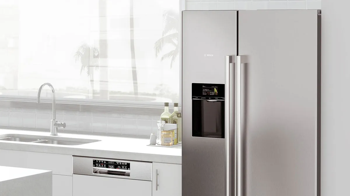 Helle, moderne Küche in Weiß mit einem freistehenden Bosch Side-by-Side Kühlschrank aus Edelstahl und einer Küchenzeile mit integriertem Bosch Geschirrspüler direkt neben der Spüle.