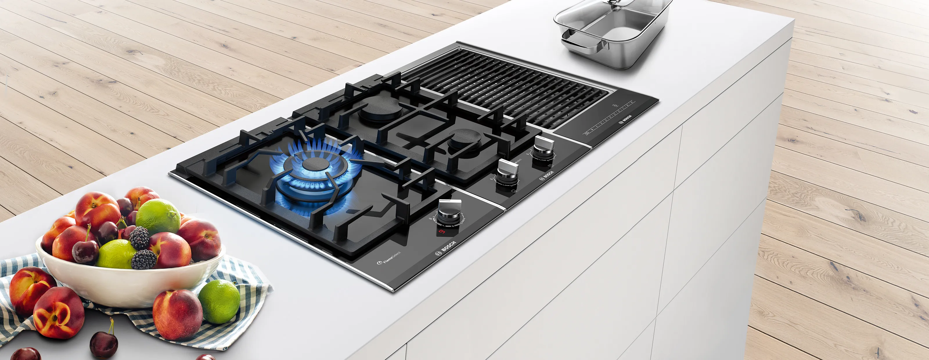 Kitchen countertop with gas stove, fruit bowl, and wooden floor.