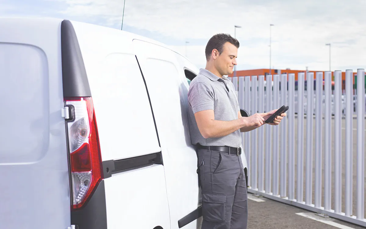 alt-Constructa Techniker steht vor seinem Fahrzeug mit Tablet in der Hand