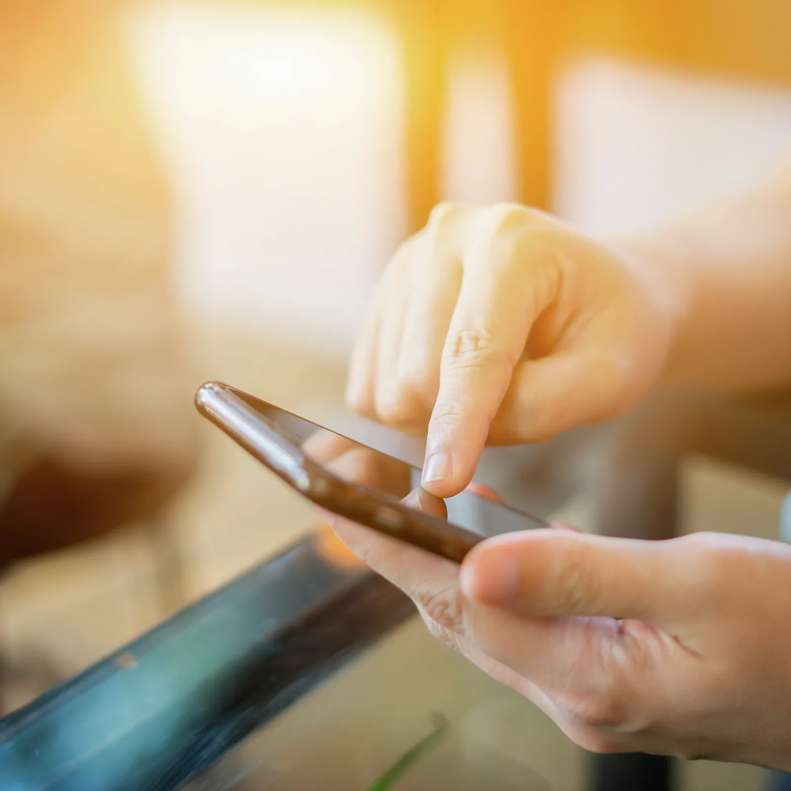 Χέρια κρατώντας ένα smartphone, κοντινή θέα, ζεστό φωτισμό, τεχνολογία, επικοινωνία.