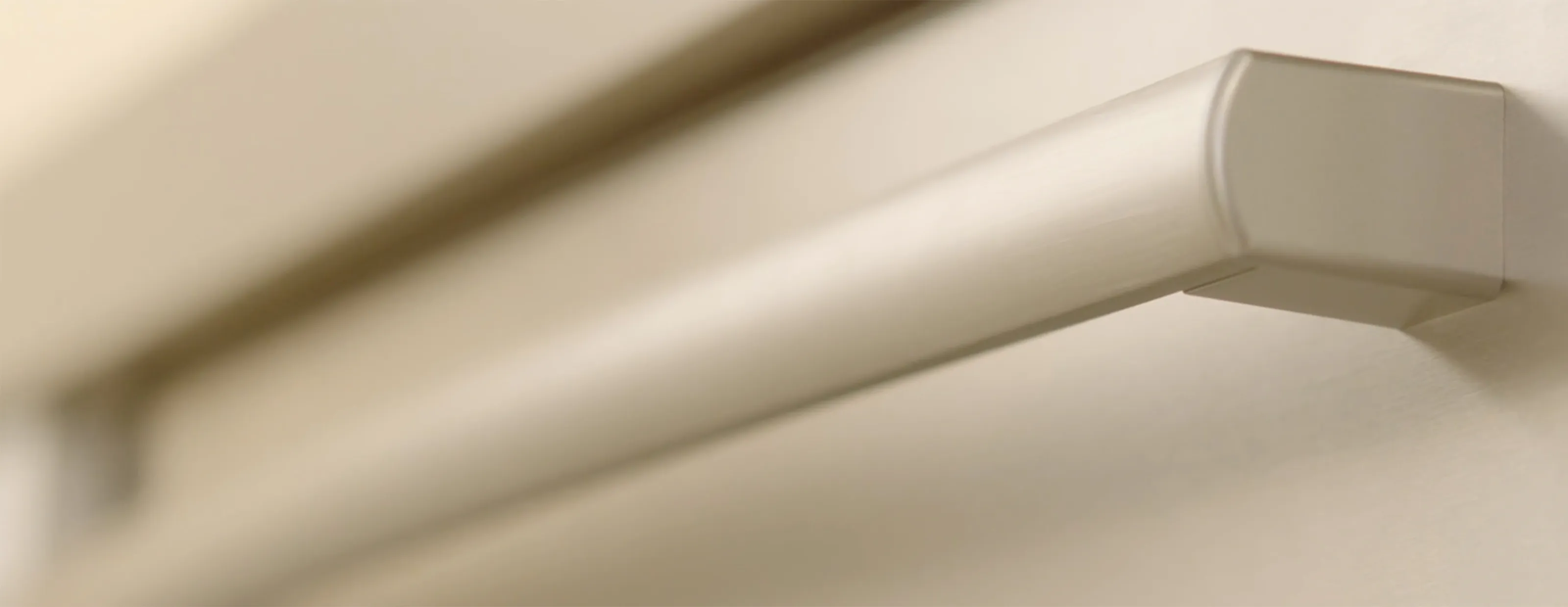Close-up of a modern kitchen Bosch handle in brushed metal on a light-colored surface.