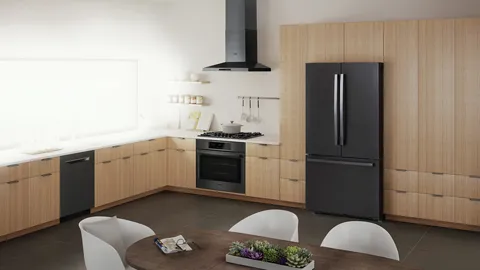 Cuisine moderne avec électroménagers noirs, armoires en bois, comptoirs blancs et table à manger avec chaises blanches et jardinière rectangulaire.