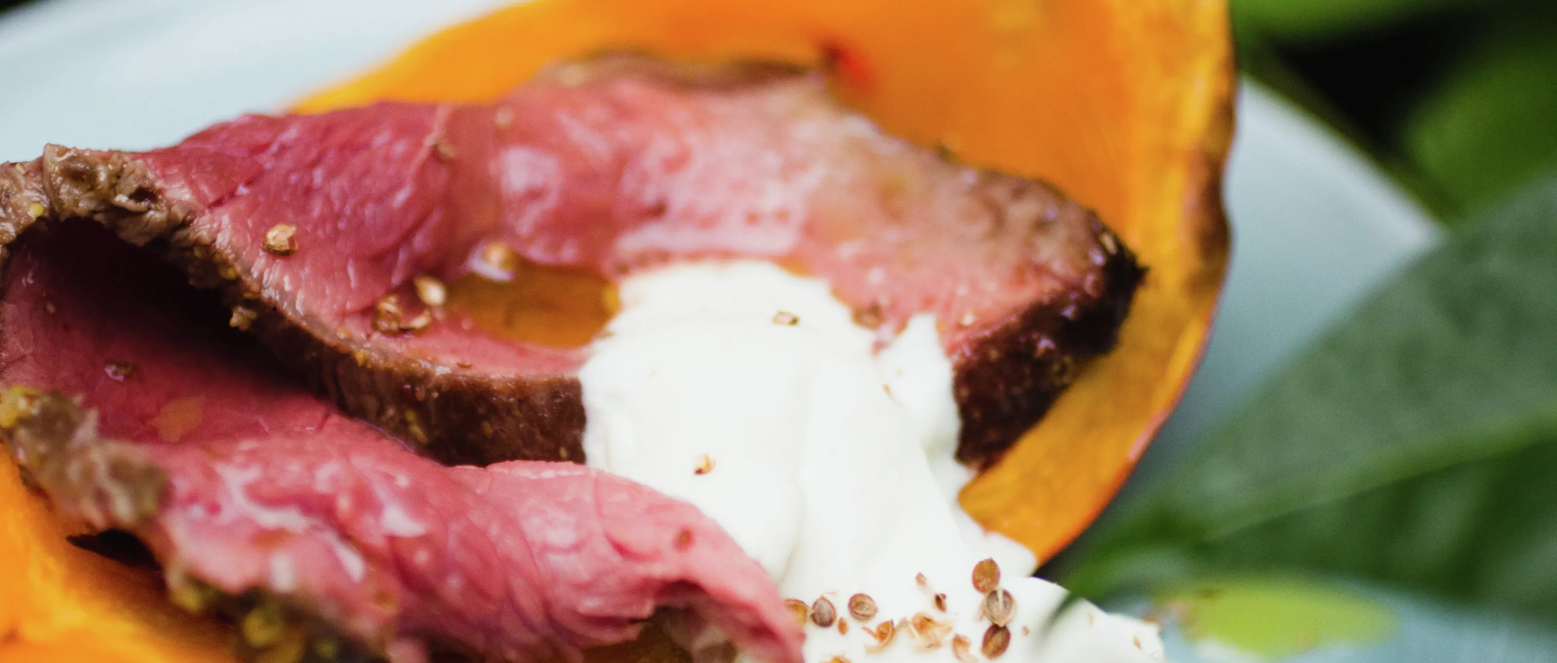 Grilled steak with orange squash, garnished with white sauce.