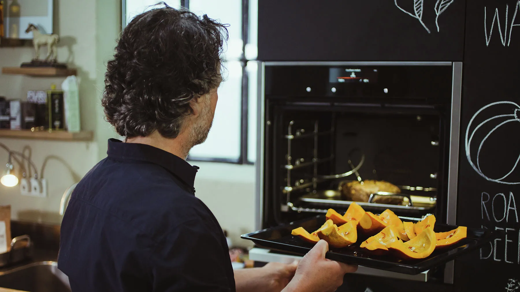 Person removing roasted vegetables from oven in kitchen.