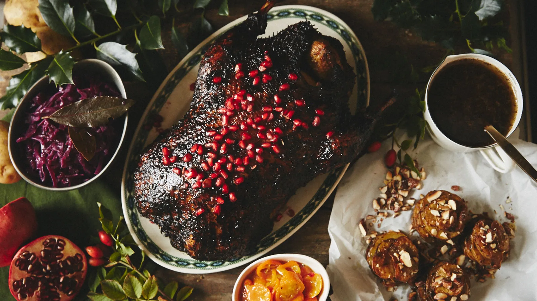 Roasted meat dish garnished with pomegranate seeds, served with side dishes of salad and desserts.