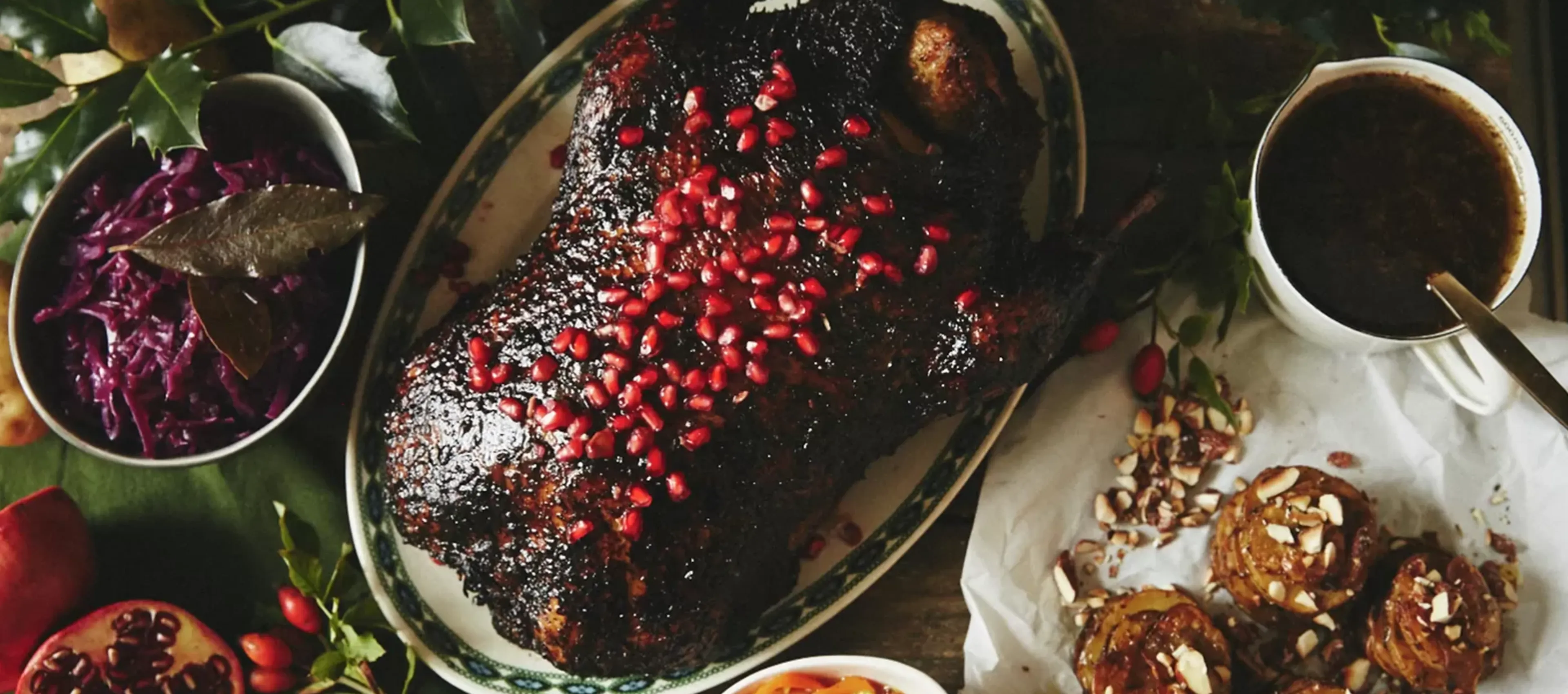 Roasted meat dish garnished with pomegranate seeds, greens, and other colorful accompaniments.