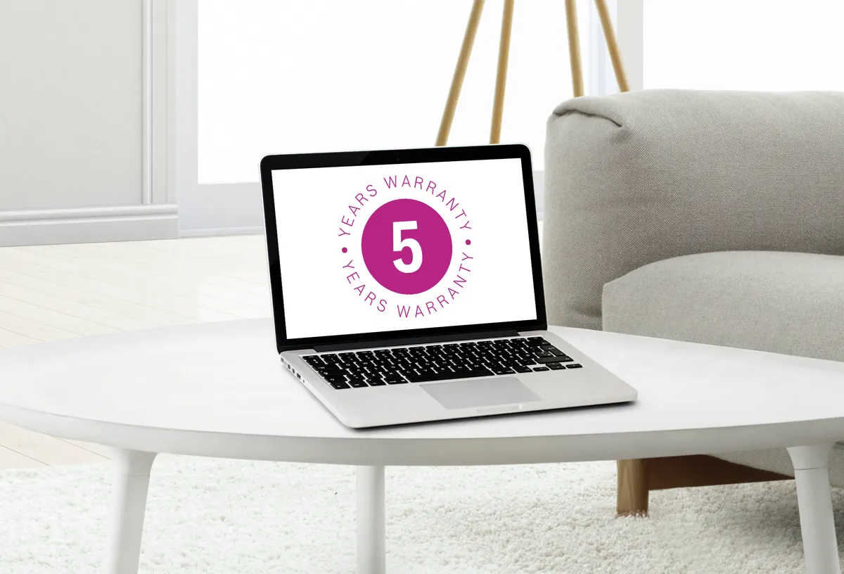 Laptop su un tavolino che mostra un badge di garanzia di 5 anni, in un salotto moderno.