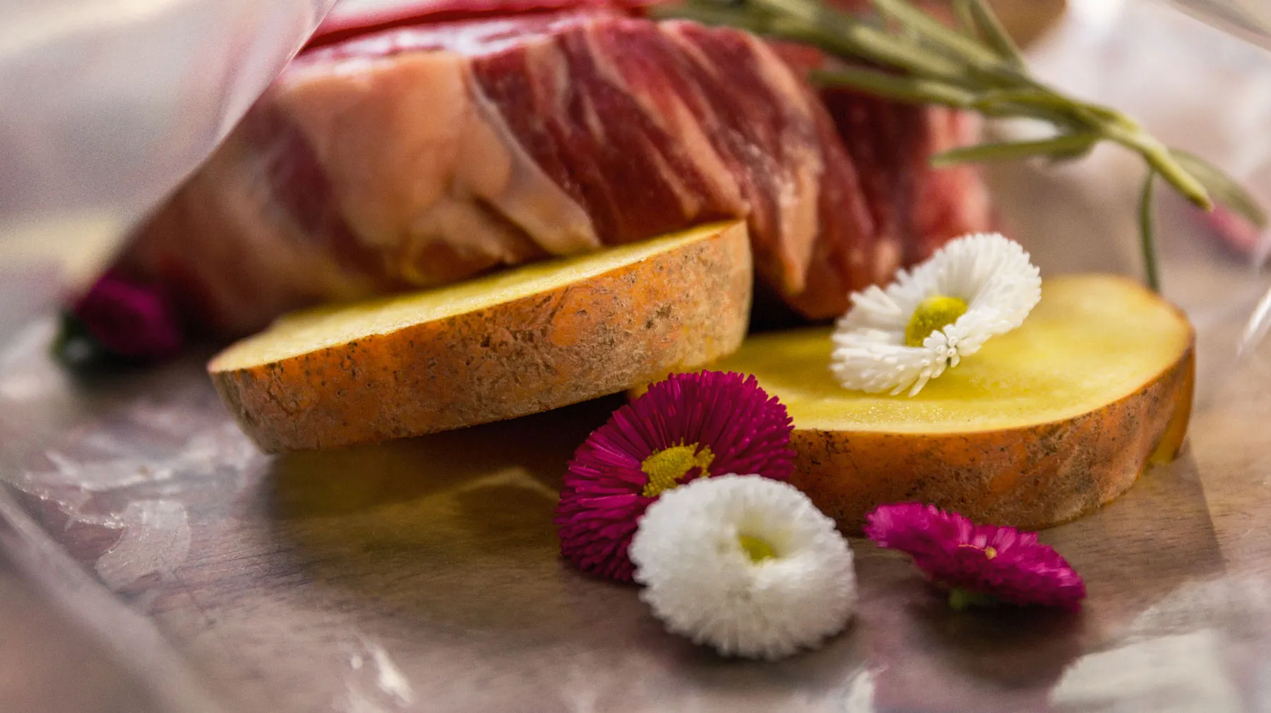 Un primo piano di carne affettata accompagnata da fette di mela fresca e fiori colorati, che esaltano la vivace presentazione.
