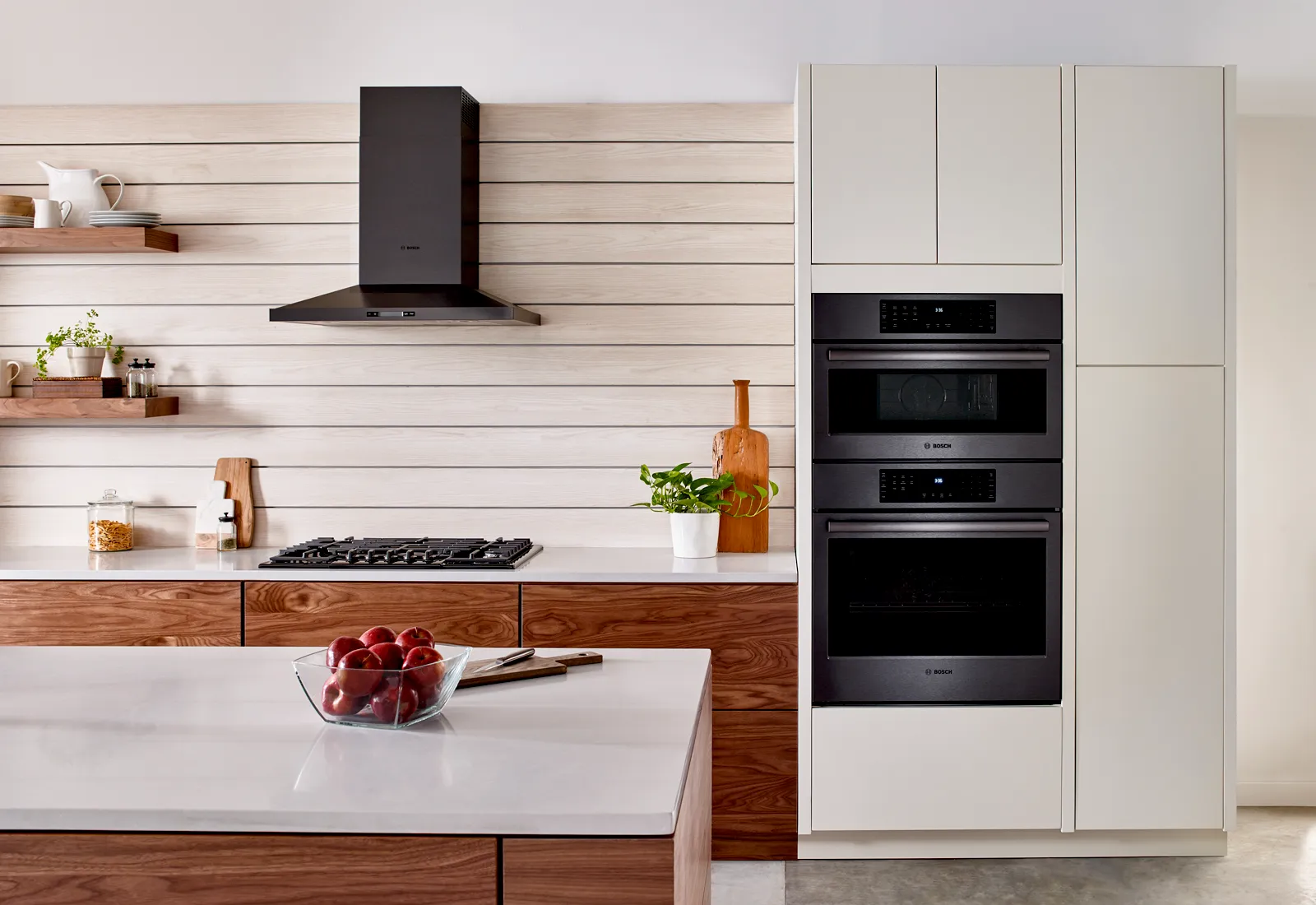 Modern kitchen with wood cabinets, white appliances, and shelves displaying decor.