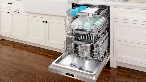 Open Bosch dishwasher with clean dishes and utensils in a modern kitchen.