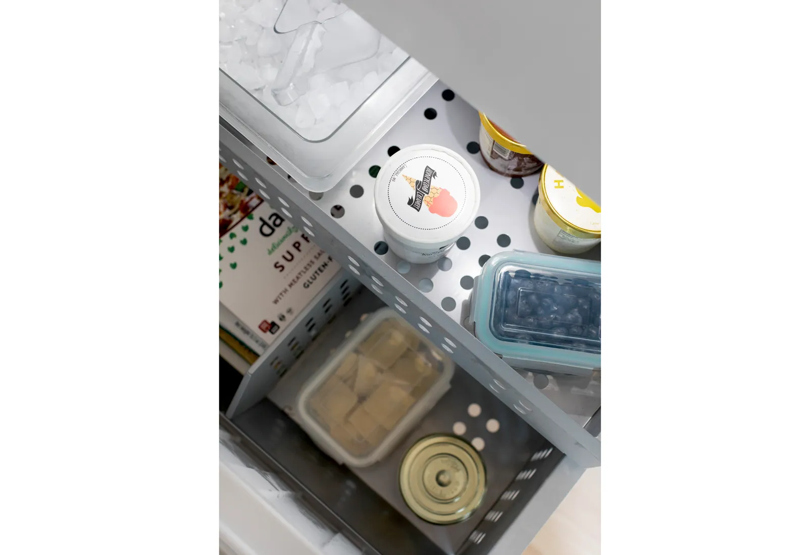 Bosch Refrigerator drawer with containers of food including canned items and yogurt tubs.