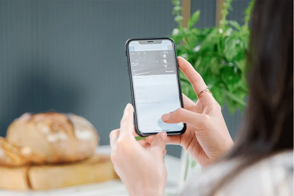 Thermador connected experience shown in smart device held by woman