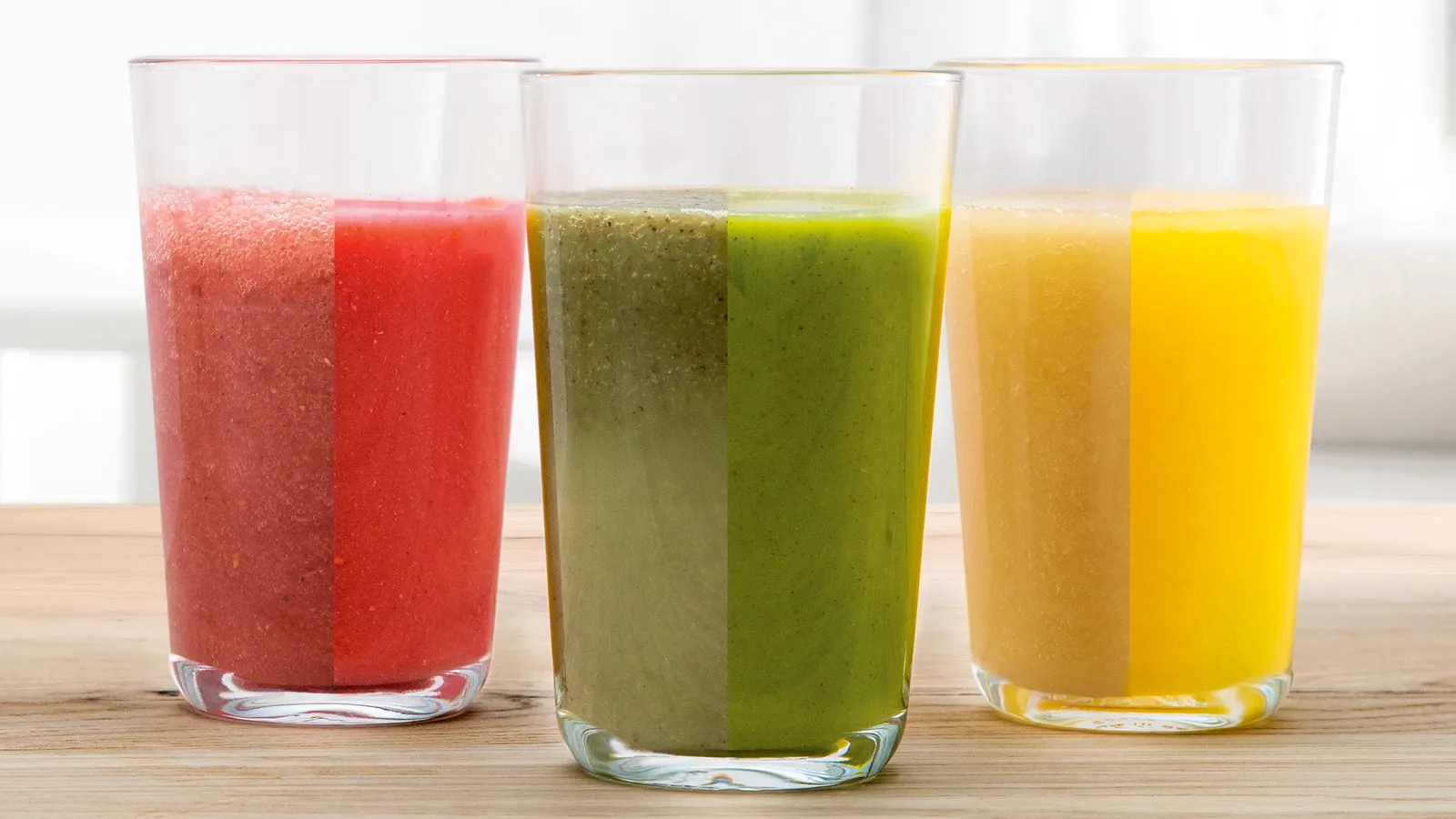 Usortizácia farebných ovocných a zeleninových smoothies v okuliaroch na drevenom stole.