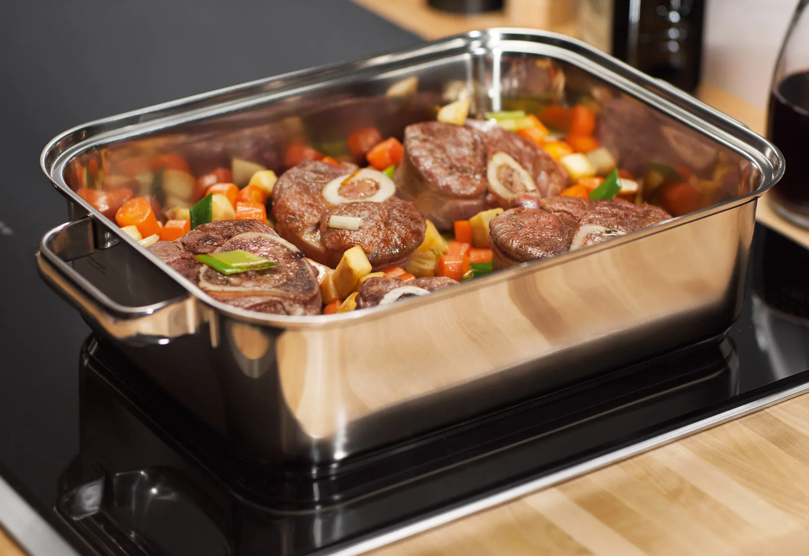Cuocere carne e verdure in un piatto di cottura in vetro su una stufa superiore.