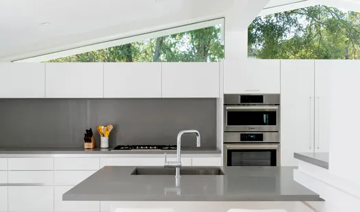 Modern kitchen with white cabinetry, Bosch stainless steel appliances, and a large window view.