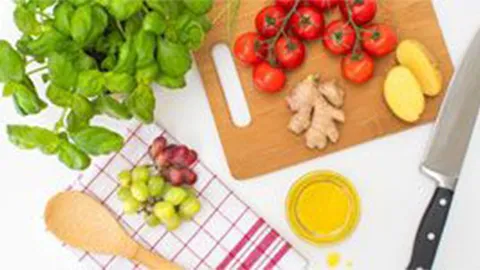 Fresh vegetables, fruits, and cooking ingredients on a wooden cutting board.