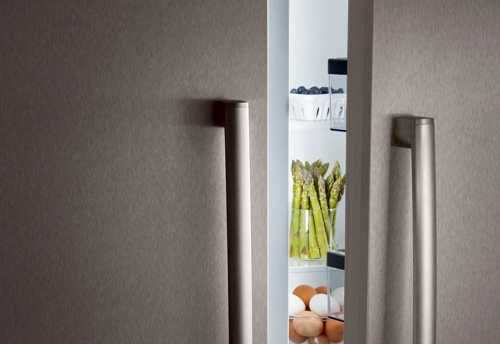 Bosch Stainless steel fridge door slightly open, revealing asparagus and eggs inside.
