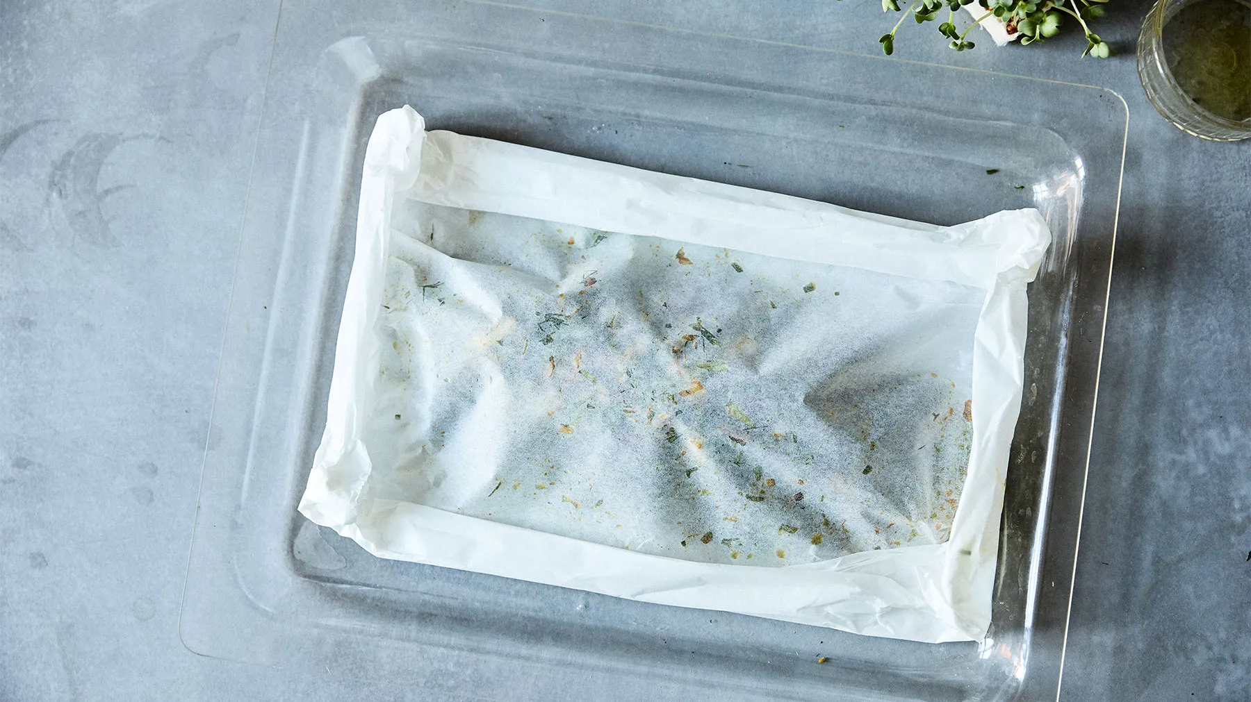 Contenitore di plastica con erbe congelate o spezie, possibilmente un metodo di conservazione o stoccaggio del cibo.