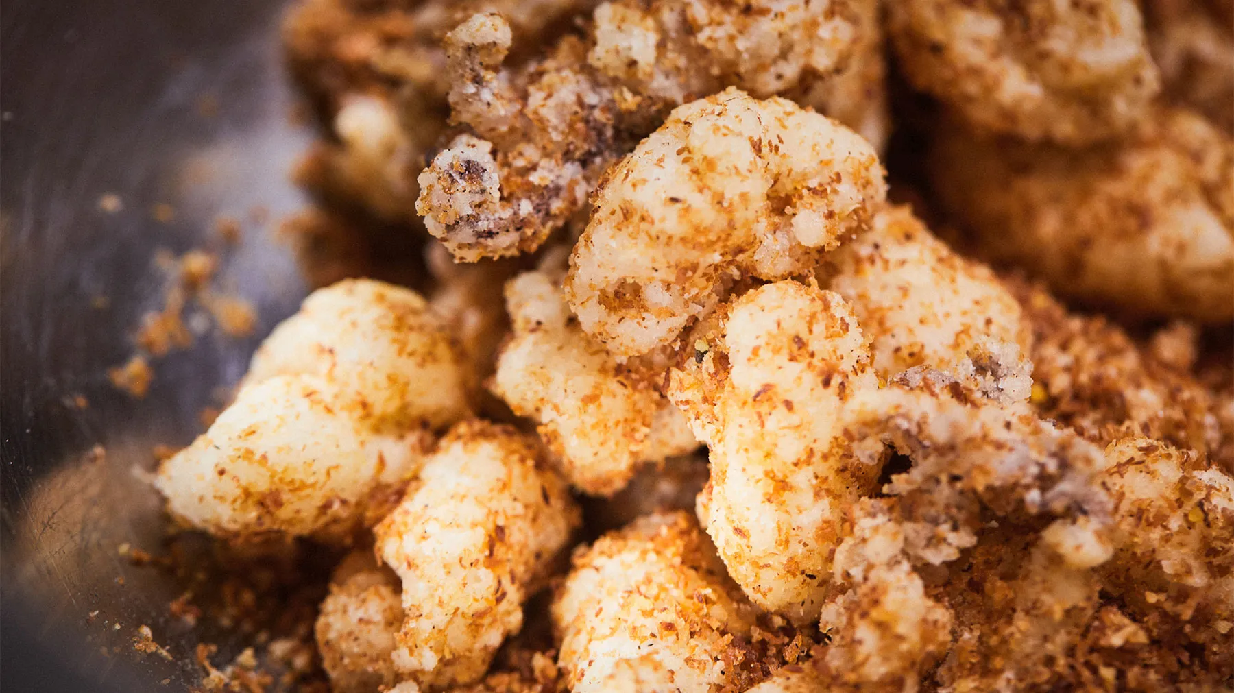 Crispy fried calamari with golden breading and seasoning on a dark background.