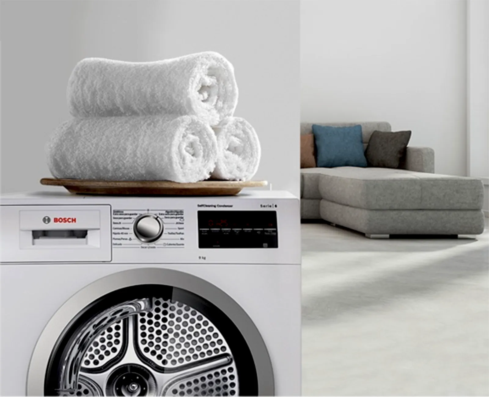 Tumble dryer in laundry room with clean towels stacked on the top