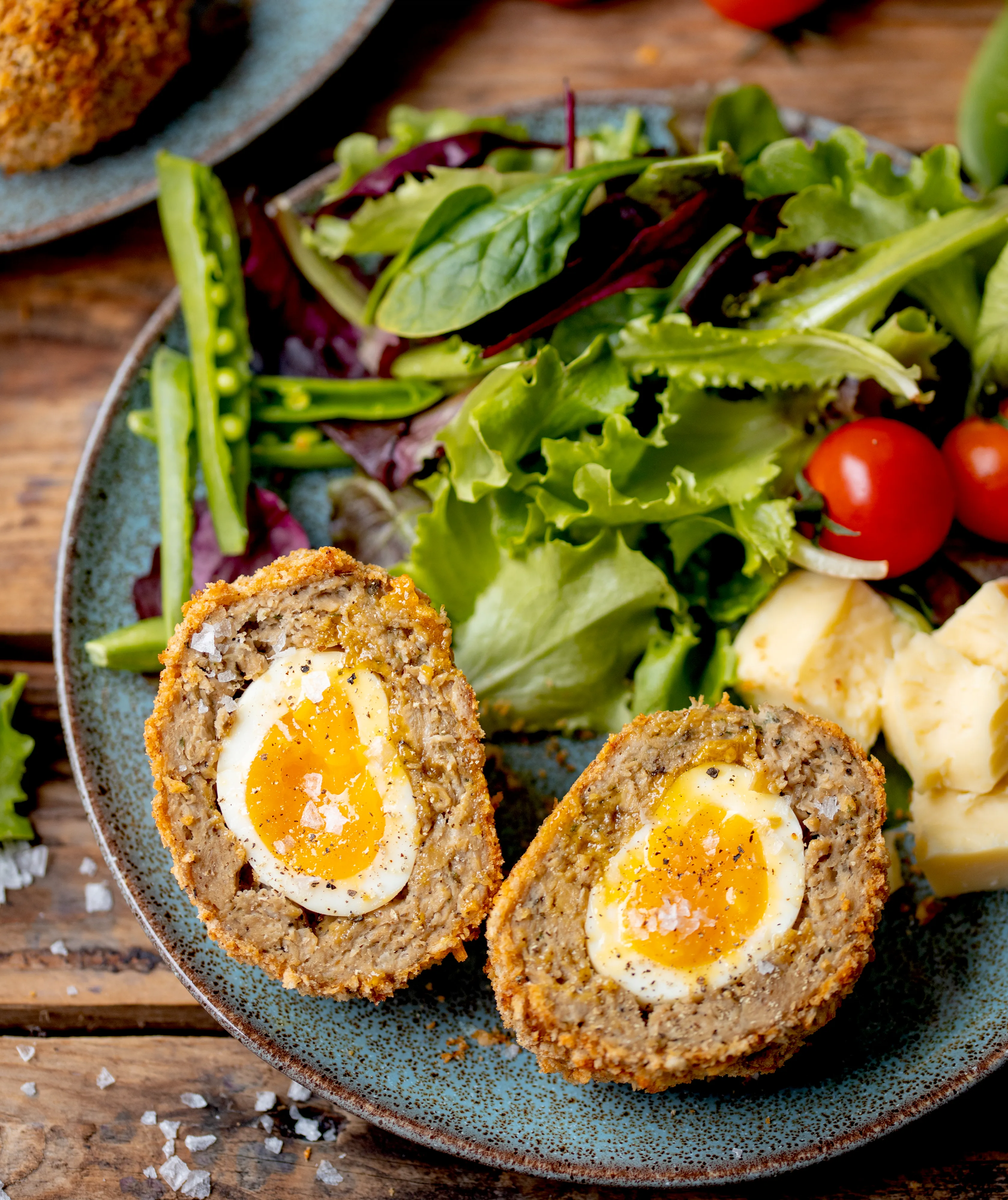 Scotch egg cut in half on plate with salad