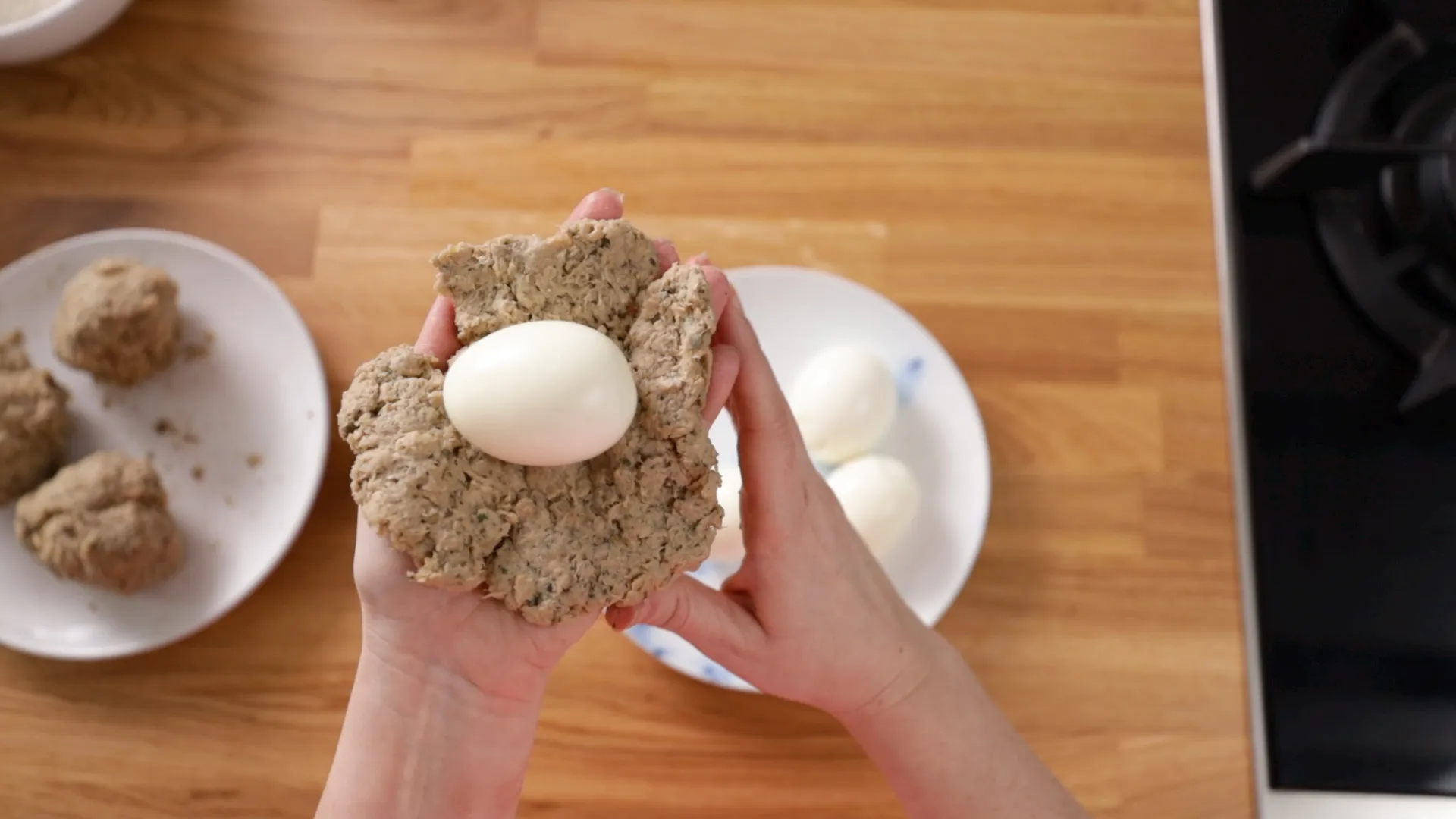Person with egg surrounded by sausagemeat