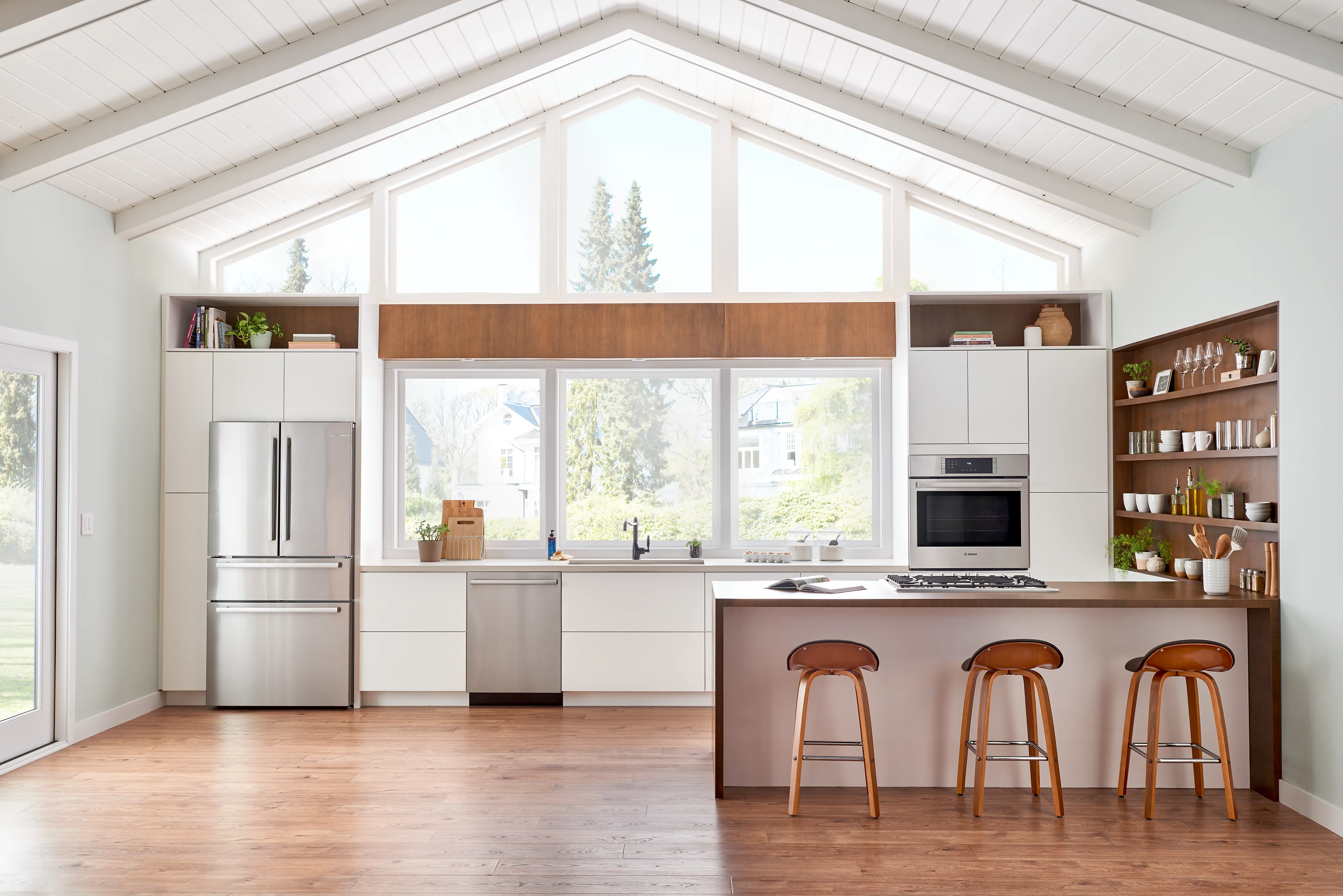 Modern kitchen with Bosch 800 Series stainless steel appliances, island, and large windows for natural light.