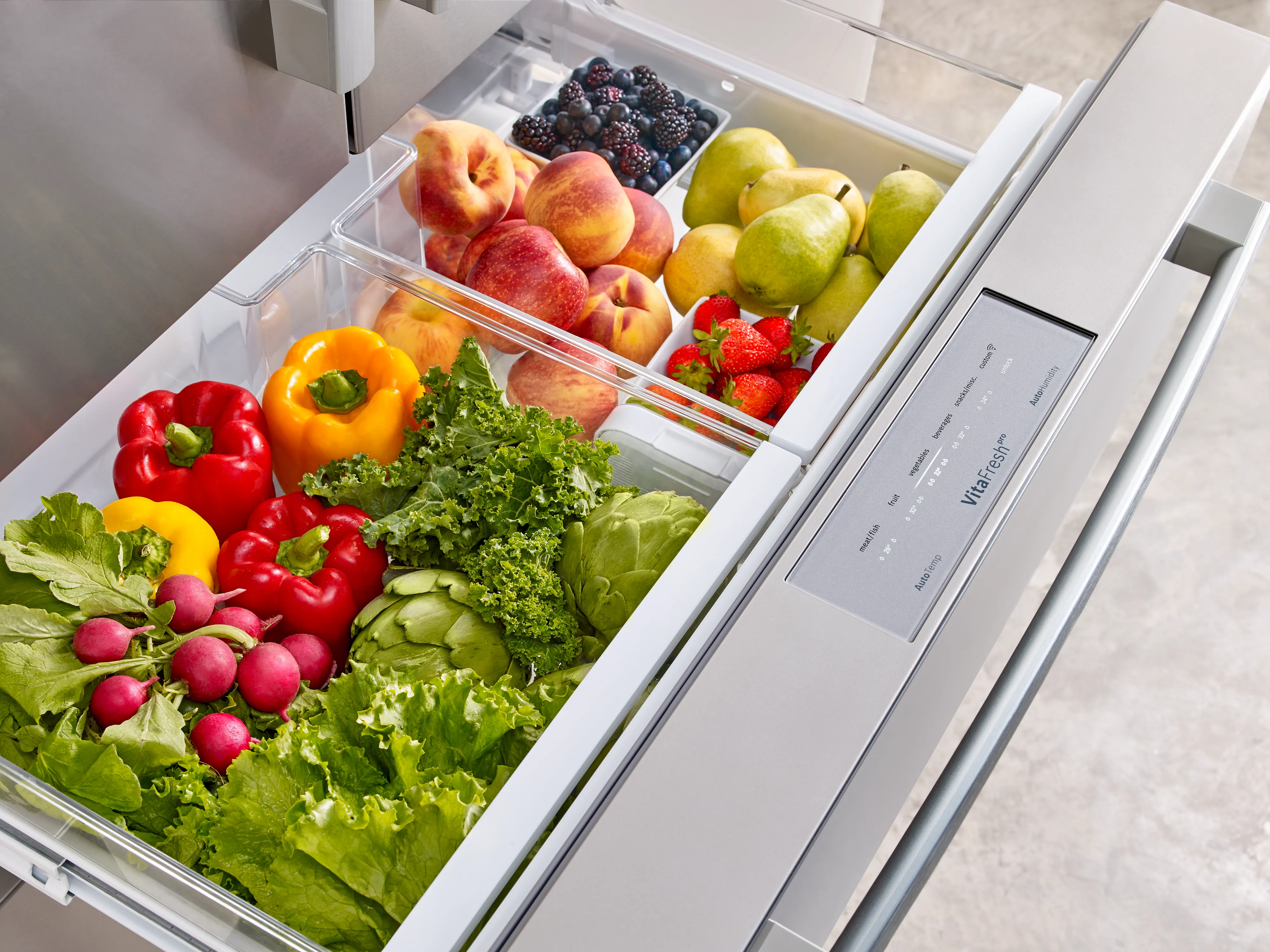 Bosch Refrigerator filled with fresh fruits and vegetables, including apples, peaches, grapes, lettuce, peppers, and radishes all inside the VitaFresh Drawer