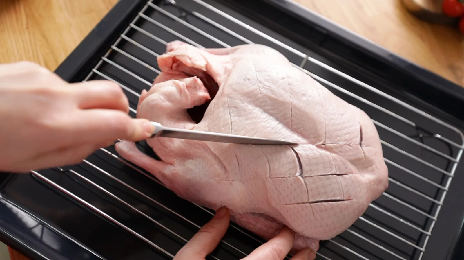 Person scoring duck breast in a criss-cross pattern