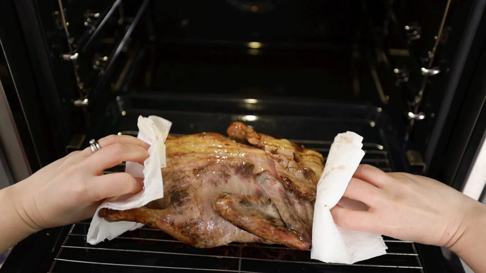 Person putting duck in the oven