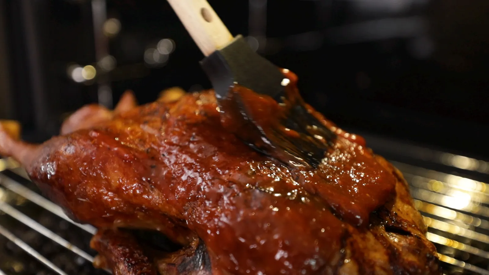 Close up of person basting duck in oven